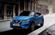 Blue Qashqai driving in between buildings